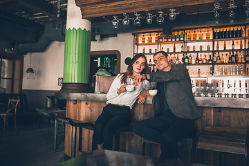 Image showing Cheerful man and woman talking, enjoying a coffee at the coffee shop, cafe, bar