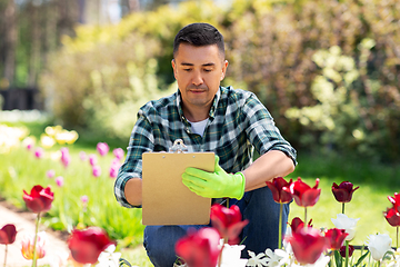 Image showing man with clipboard and flowers at summer garden