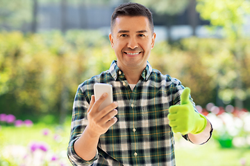 Image showing man with smartphone showing thumbs up at garden