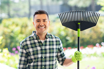 Image showing happy middle-aged man with leaf rake at garden