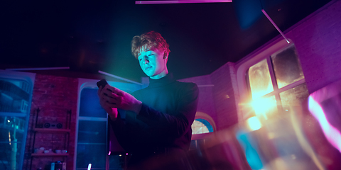 Image showing Cinematic portrait of handsome young man in neon lighted interior