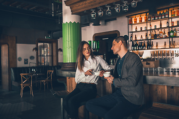 Image showing Cheerful man and woman talking, enjoying a coffee at the coffee shop, cafe, bar