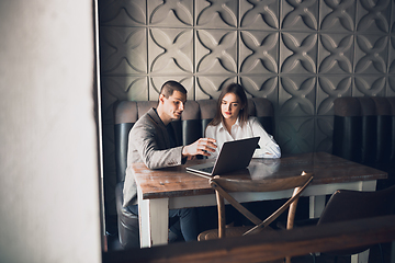 Image showing Cheerful man and woman talking, working at the coffee shop, cafe