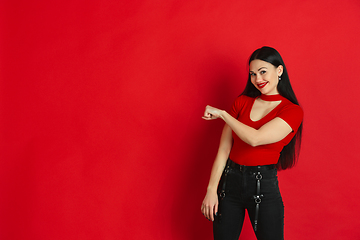 Image showing Caucasian young woman\'s monochrome portrait on red studio background, emotional and expressive