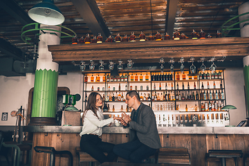 Image showing Cheerful man and woman talking, enjoying a coffee at the coffee shop, cafe, bar