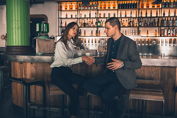 Image showing Cheerful man and woman talking, enjoying a coffee at the coffee shop, cafe, bar