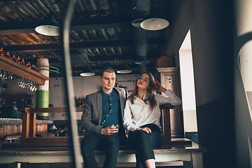 Image showing Cheerful man and woman talking, enjoying, having fun at bar, cafe