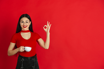 Image showing Caucasian young woman\'s monochrome portrait on red studio background, emotional and expressive