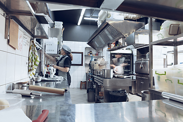 Image showing Behind the scenes of brands. The chef cooking in a professional kitchen of a restaurant meal for client or delivery. Motion.