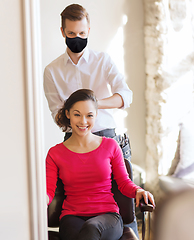 Image showing happy woman with stylist making hairdo at salon