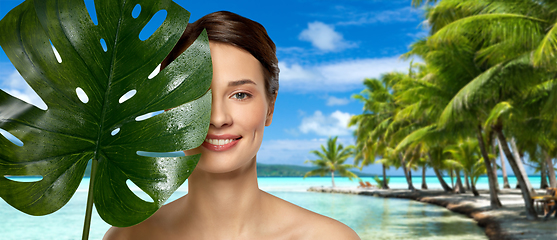 Image showing young woman with green monstera leaf on beach