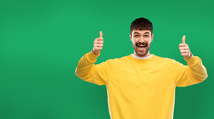 Image showing happy man showing thumbs up over green background