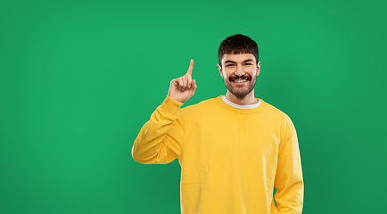 Image showing happy man pointing finger up over green