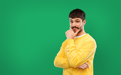 Image showing thinking young man in yellow sweatshirt