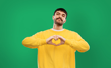 Image showing young man in yellow sweatshirt l making hand heart