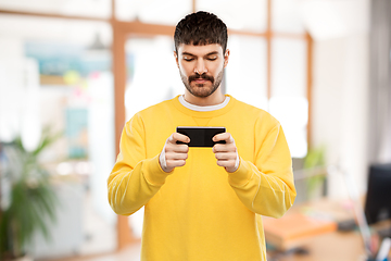 Image showing young man playing game on smartphone