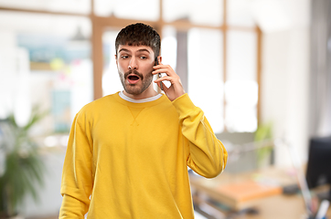 Image showing shocked young man calling on smartphone