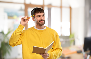 Image showing thinking man with diary and pencil over office