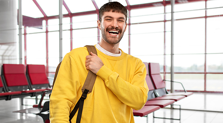 Image showing happy smiling young man with backpack over airport