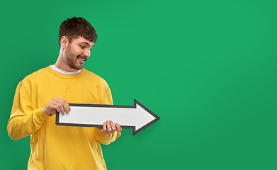 Image showing smiling man pointing big arrow to right over green