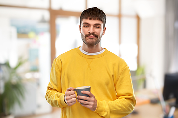 Image showing displeased young man with coffee cup at office