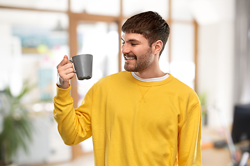 Image showing happy smiling young man with coffee cup at office