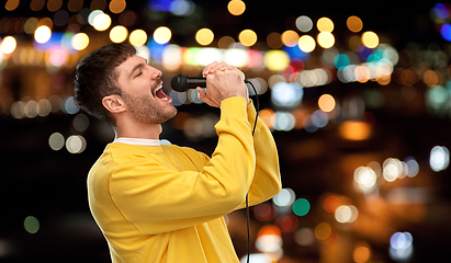 Image showing man with microphone singing over night city lights