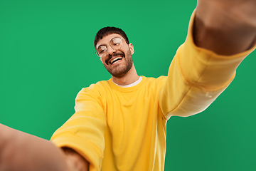 Image showing happy young man in yellow sweatshirt making selfie