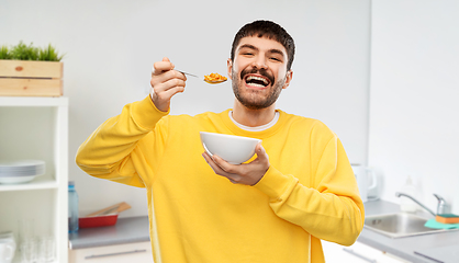 Image showing happy smiling young man eating cereals