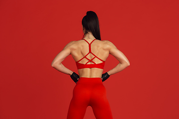 Image showing Beautiful young female athlete practicing on red studio background, monochrome portrait