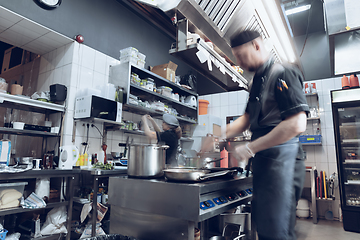 Image showing Behind the scenes of brands. The chef cooking in a professional kitchen of a restaurant meal for client or delivery. Motion.