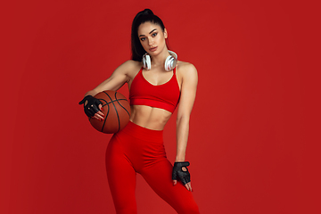 Image showing Beautiful young female athlete practicing on red studio background, monochrome portrait