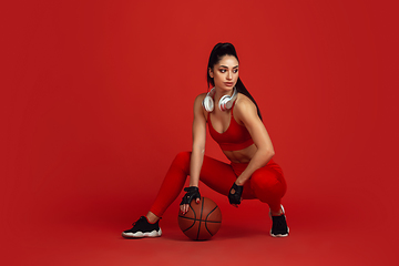 Image showing Beautiful young female athlete practicing on red studio background, monochrome portrait