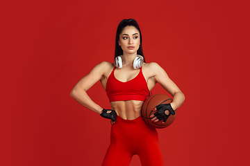 Image showing Beautiful young female athlete practicing on red studio background, monochrome portrait