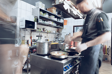 Image showing Behind the scenes of brands. The chef cooking in a professional kitchen of a restaurant meal for client or delivery. Motion.