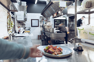 Image showing Behind the scenes of brands. The chef cooking in a professional kitchen of a restaurant meal for client or delivery. Motion.