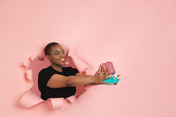 Image showing Cheerful young woman poses in torn coral paper hole background, emotional and expressive