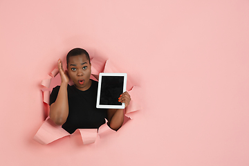 Image showing Cheerful young woman poses in torn coral paper hole background, emotional and expressive