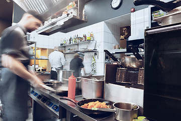 Image showing Behind the scenes of brands. The chef cooking in a professional kitchen of a restaurant meal for client or delivery. Motion.