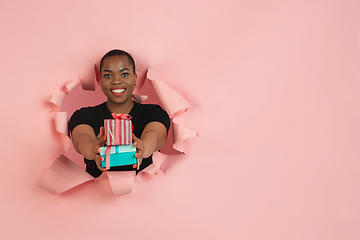 Image showing Cheerful young woman poses in torn coral paper hole background, emotional and expressive