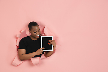 Image showing Cheerful young woman poses in torn coral paper hole background, emotional and expressive