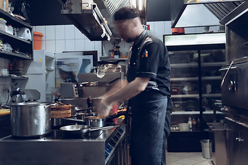 Image showing Behind the scenes of brands. The chef cooking in a professional kitchen of a restaurant meal for client or delivery. Motion.