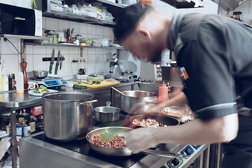 Image showing Behind the scenes of brands. The chef cooking in a professional kitchen of a restaurant meal for client or delivery. Motion.