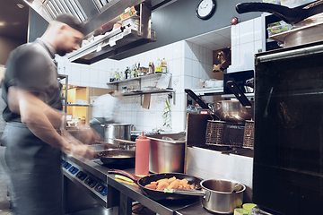 Image showing Behind the scenes of brands. The chef cooking in a professional kitchen of a restaurant meal for client or delivery. Motion.