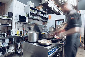 Image showing Behind the scenes of brands. The chef cooking in a professional kitchen of a restaurant meal for client or delivery. Motion.