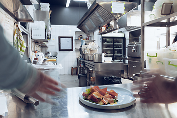 Image showing Behind the scenes of brands. The chef cooking in a professional kitchen of a restaurant meal for client or delivery. Motion.