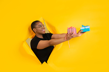 Image showing Cheerful young woman poses in torn yellow paper hole background, emotional and expressive