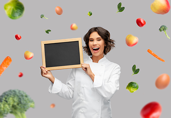 Image showing happy female chef holding chalkboard over food