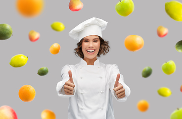 Image showing happy female chef showing thumbs up over fruits