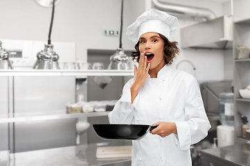 Image showing surprised female chef in toque with frying pan